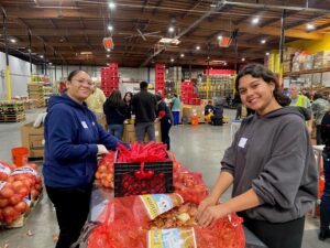 ITD employees smiling while they sort through a bag of onions