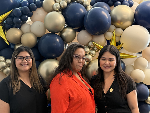 3 women smiling and standing in front of balloon display