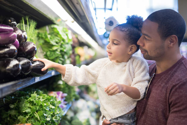 Father and Daughter picking out eggplants in a grocery store