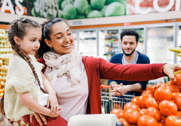 Mother and daughter picking out oranges in a grocery store